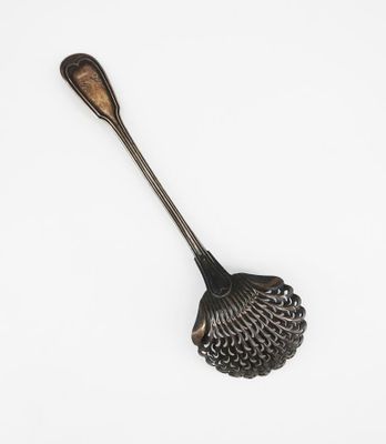 une cuillère avec un manche en métal posée sur une surface blanche