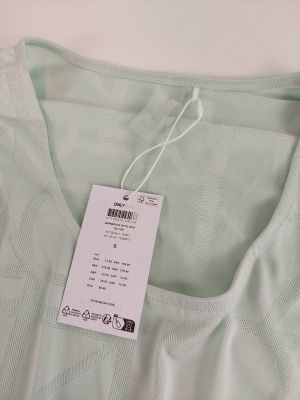 l'étiquette située en haut d'un t-shirt vert est fixée à une étiquette blanche
