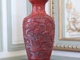 un vase rouge posé sur une table devant un miroir