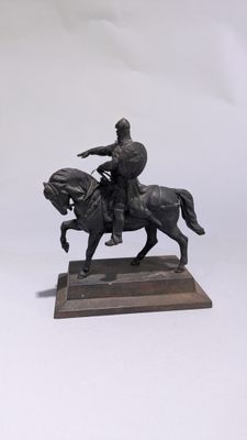 une statue représentant un homme à cheval, posée sur un socle en bois