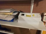 a stack of papers on a shelf next to a laptop