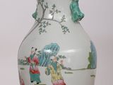 a white vase with a painting on it sitting on a table