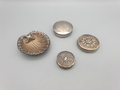 trois boutons en argent et un coquillage en argent sur un fond blanc
