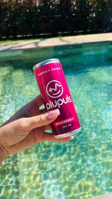 une personne tenant une canette de Red Bull près d'une piscine