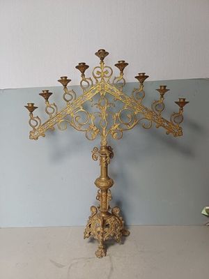 a gold colored metal cross with candles on it