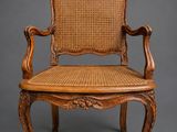 a wooden chair with wicker seat and arm rest
