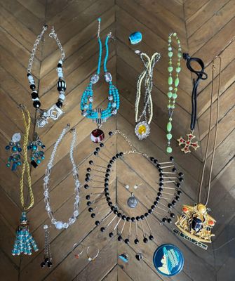 Plusieurs colliers et boucles d'oreilles sont disposés sur un parquet.