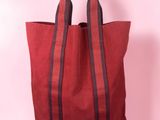 a red and black tote bag on a pink background