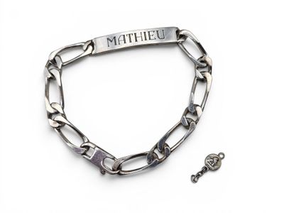 un gros plan d'un bracelet à maillons orné d'une clé, sur un fond blanc