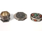 three silver rings and a ring on a white surface