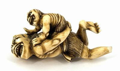 an antique ivory figurine of a man wrestling a tiger