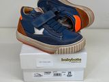 des chaussures de bébé bleues et orange pour garçon posées sur une boîte blanche
