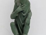 statue of a woman sitting on a rock with her hands on her chest
