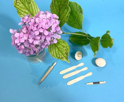 purple flowers in a vase with a spoon, spoons, and other tools