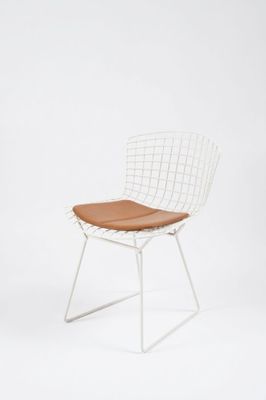 une photo d'une chaise en fil métallique blanche avec un coussin d'assise marron