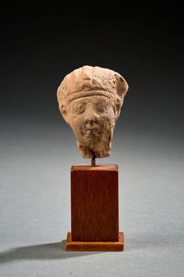un gros plan sur une statue représentant une tête posée sur un socle en bois