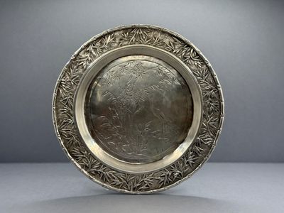 une assiette ancienne en argent, ornée d'un motif floral sur le bord