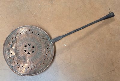 a metal strainer with a handle on the floor