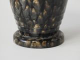 a black and gold vase sitting on a white surface