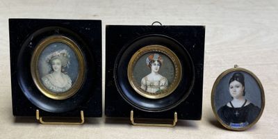 trois portraits miniatures de femmes dans des cadres noirs, posés sur une table