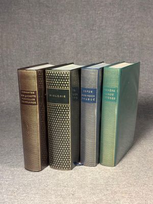 four books are lined up in a row on a gray surface