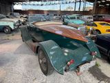 many old cars parked in a garage with a surfboard on the back of the car