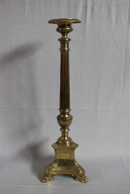 brass candle holder with a candle on a white background