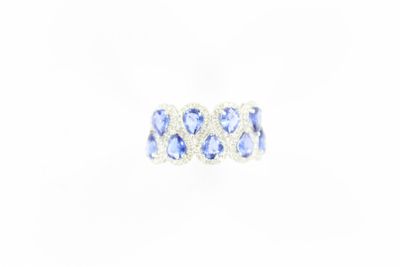 un gros plan d'une bague ornée de pierres bleues sur fond blanc