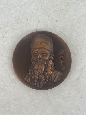 a bronze medallion of a man with a beard and a hat