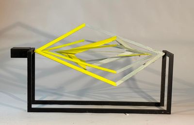 a glass sculpture with yellow sticks sticking out of it
