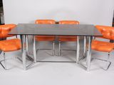 an image of a glass table with orange chairs and a white backdrop