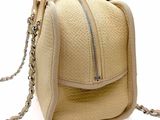 a beige purse with a chain around it on a white surface