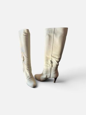une paire de bottes en cuir blanc posées sur une surface blanche, avec un fond blanc