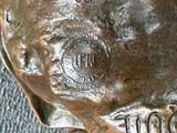 une statue en bronze représentant un chien, sur laquelle figure un nom