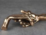 figurine en laiton représentant une main tenant un pistolet posée sur une table