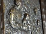 a metal relief of a woman and child on a wall