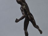 bronze statue of a man holding a tennis racquet on a wooden base