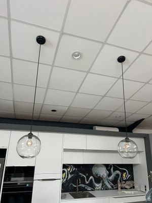 une cuisine avec des placards blancs et une fresque murale en noir et blanc sur le mur