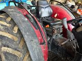 a red tractor parked in a barn with a large tire