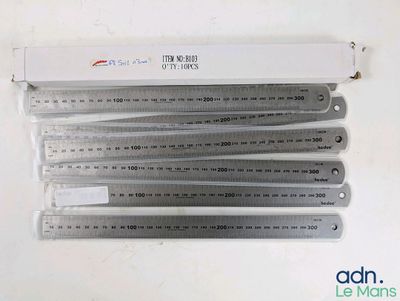 six règles métalliques sont empilées les unes sur les autres sur une table