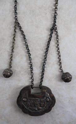 un gros plan d'un collier avec une pièce suspendue à une chaîne