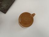 a brown cup sitting on a white table next to a knife