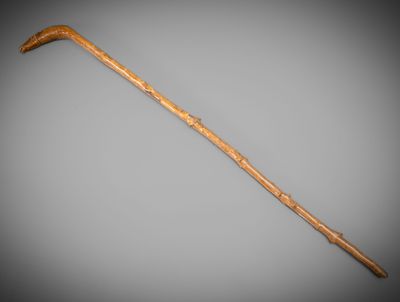 an old wooden stick with a long handle on a gray background