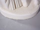 a white statue of a woman holding a fan on a table