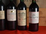 several bottles of wine are lined up on a red table cloth