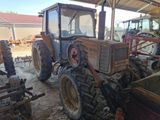 a tractor that is sitting in the dirt in a barn