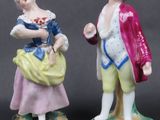 two figurines of a man and a woman standing next to each other