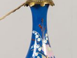 un vase bleu muni d'une anse dorée, posé sur une table en bois