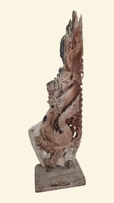 une statue représentant un dragon assis sur un socle en bois