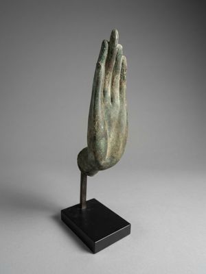 a bronze statue of a praying hand on a black stand